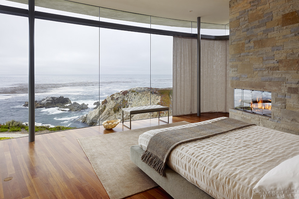 Bedroom - contemporary medium tone wood floor bedroom idea in Other with a stone fireplace and a corner fireplace