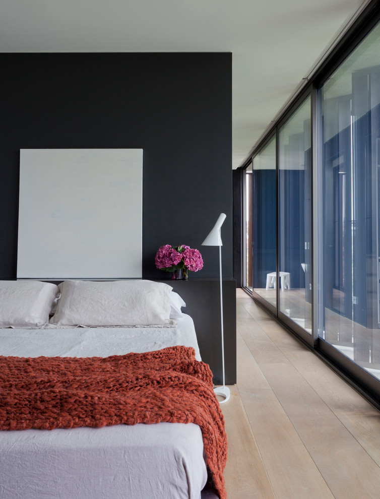 Стильный дизайн: спальня в стиле модернизм с черными стенами и светлым паркетным полом - последний тренд