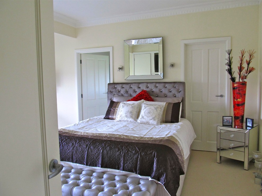 Modelo de dormitorio principal actual de tamaño medio con paredes beige y moqueta