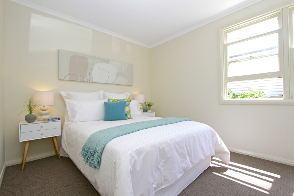 This is an example of a small modern guest bedroom in Hobart with beige walls and carpet.