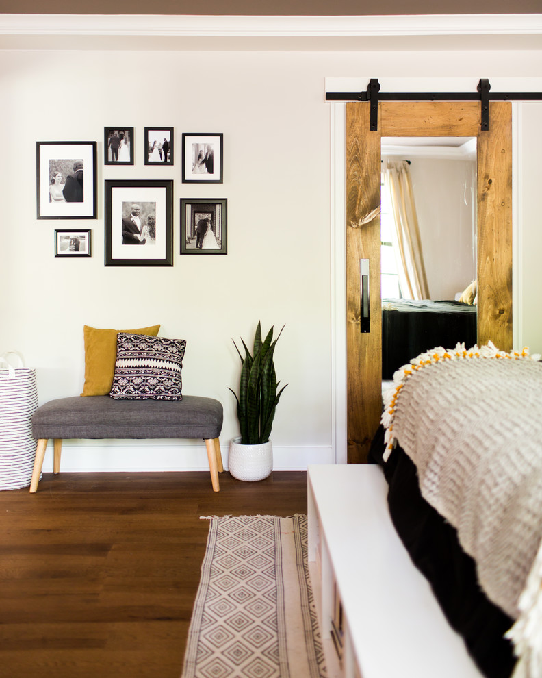 Modelo de dormitorio principal clásico renovado grande sin chimenea con paredes beige, suelo de madera en tonos medios y suelo marrón