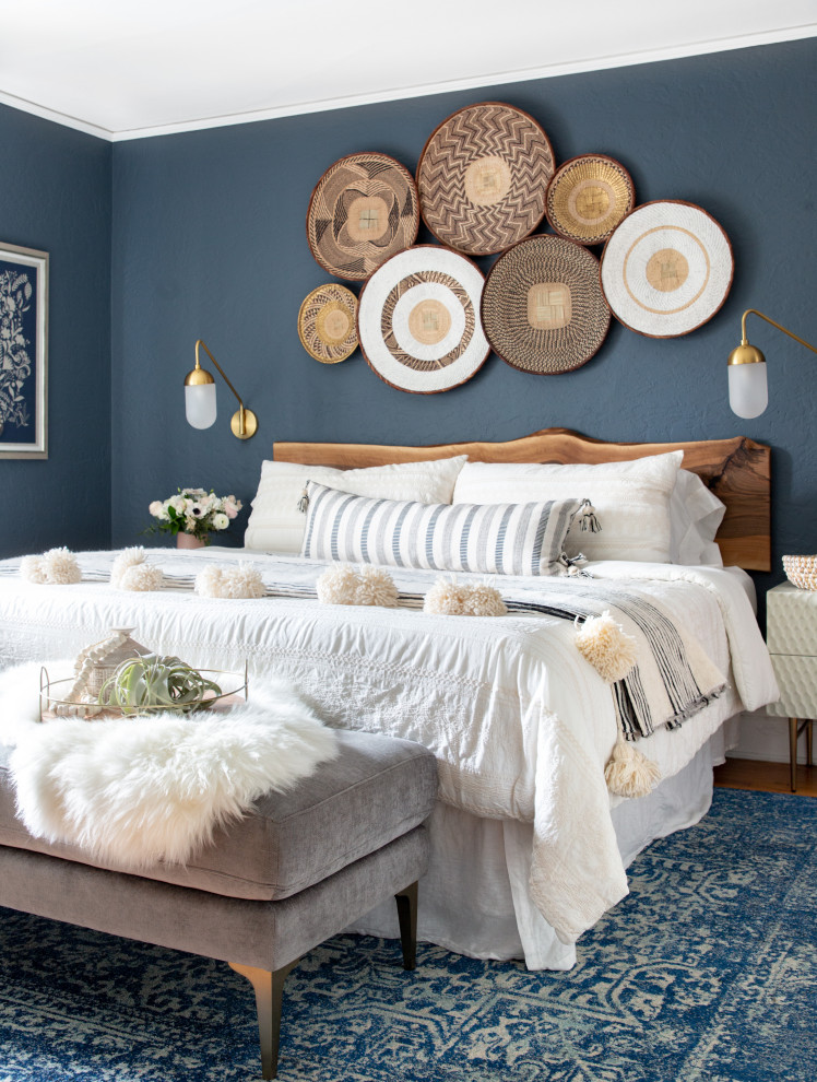 Modelo de dormitorio bohemio de tamaño medio con paredes azules, suelo de madera en tonos medios y suelo marrón