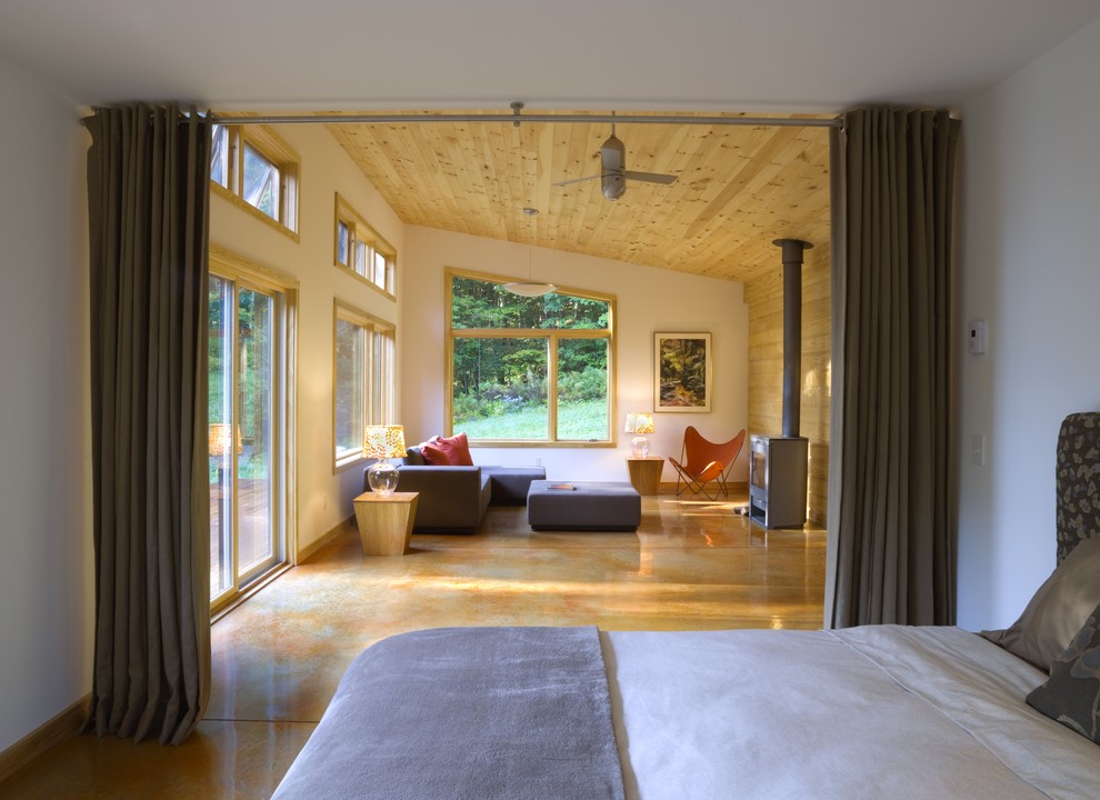 Foto de dormitorio minimalista con paredes blancas, suelo de cemento y estufa de leña