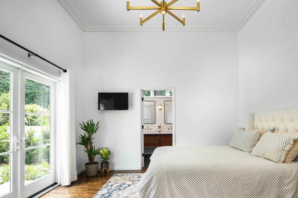 Foto di una camera matrimoniale classica di medie dimensioni con pareti bianche, pavimento in legno massello medio, pavimento marrone e TV