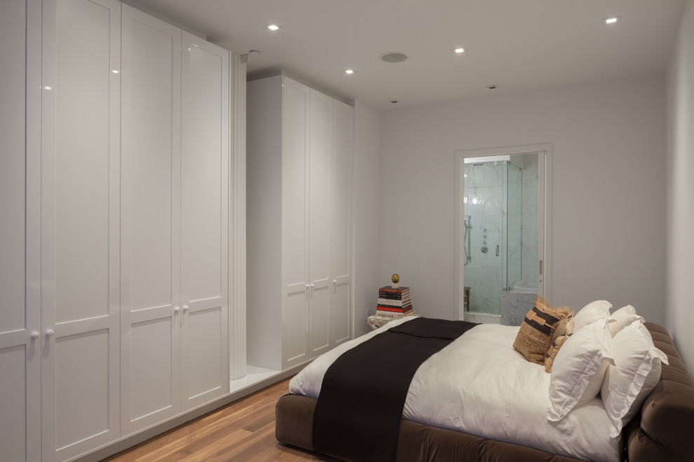 This is an example of a medium sized contemporary master bedroom in New York with white walls, medium hardwood flooring, no fireplace and brown floors.