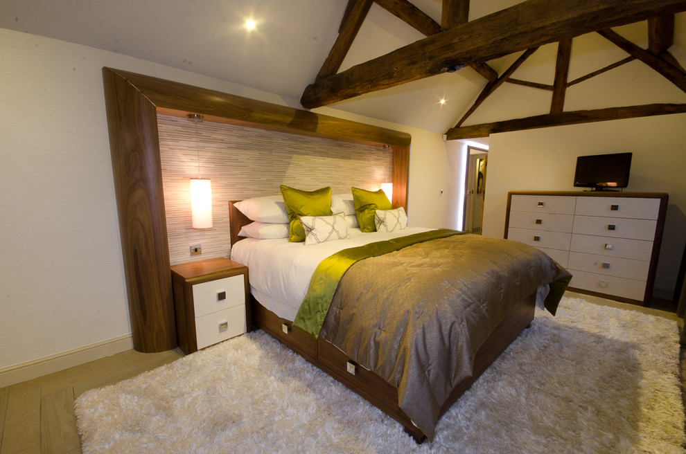 This is an example of a large farmhouse master bedroom in West Midlands with beige walls and medium hardwood flooring.
