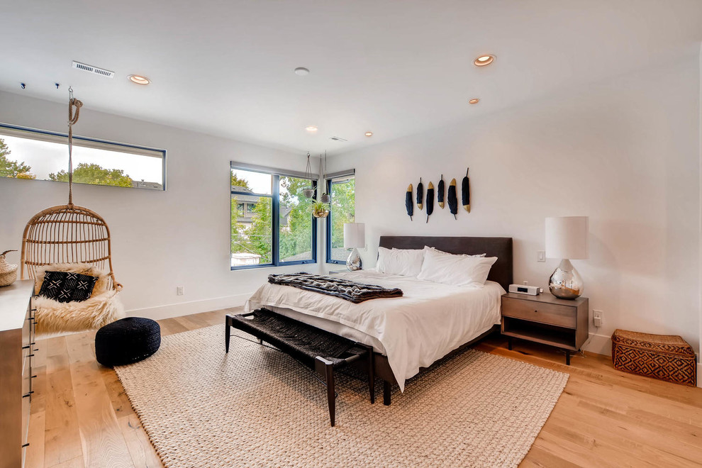 Example of a trendy medium tone wood floor and brown floor bedroom design in Denver with white walls