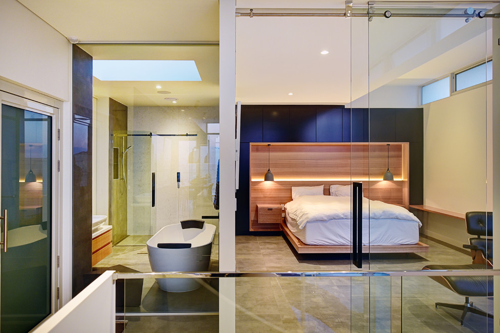Immagine di una camera da letto design con pareti bianche e pavimento grigio