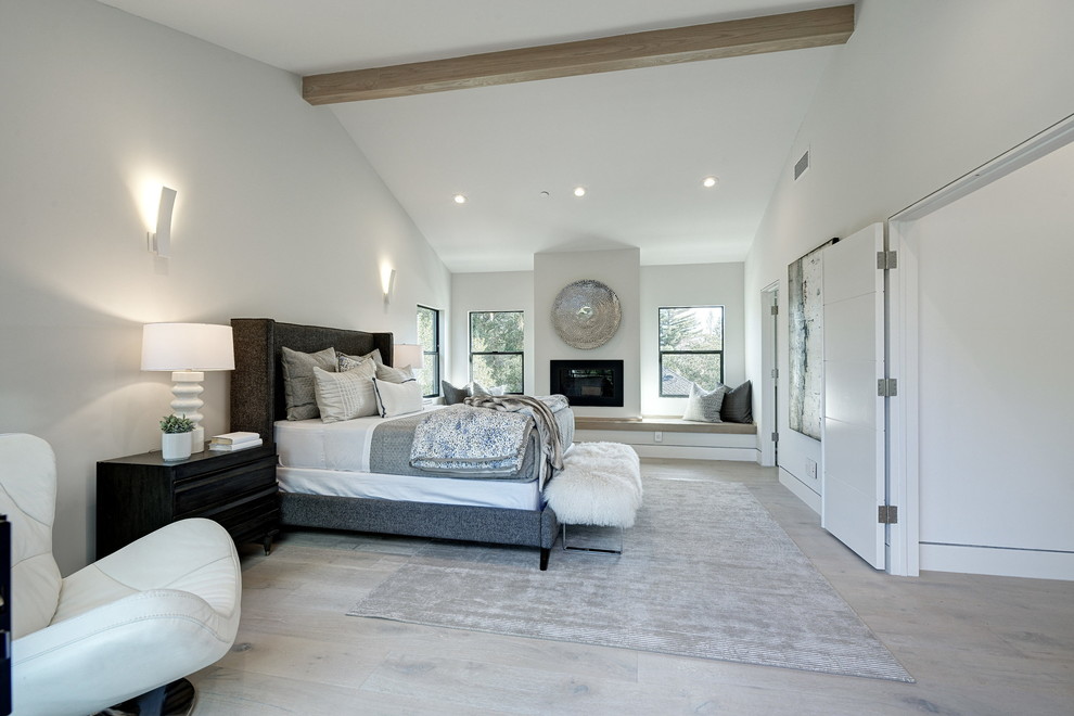 Источник вдохновения для домашнего уюта: большая хозяйская спальня в стиле неоклассика (современная классика) с белыми стенами, светлым паркетным полом, горизонтальным камином, фасадом камина из металла и серым полом