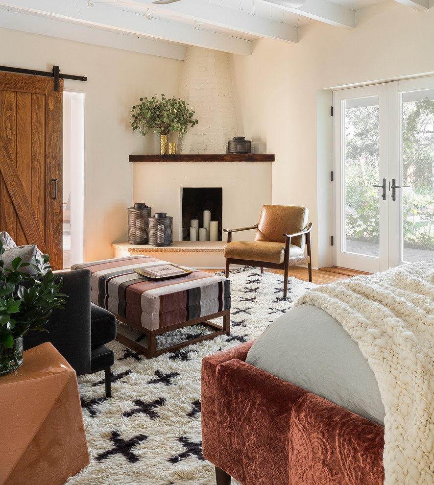 Modernes Hauptschlafzimmer mit weißer Wandfarbe, braunem Holzboden, Eckkamin und Kaminumrandung aus Backstein in Albuquerque