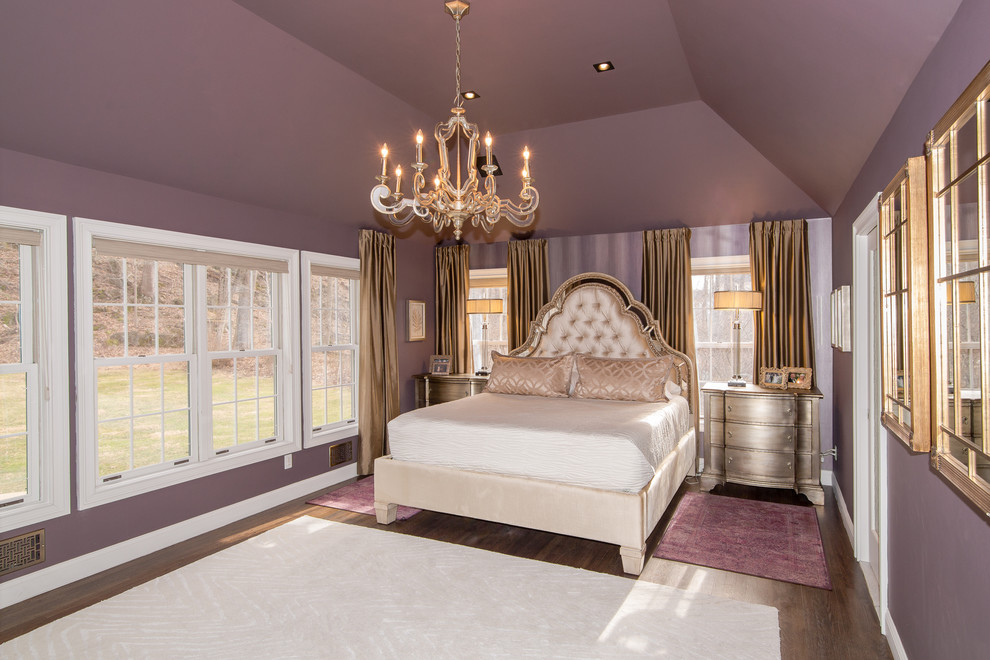 Cette image montre une grande chambre parentale avec un mur violet, parquet foncé et un sol marron.