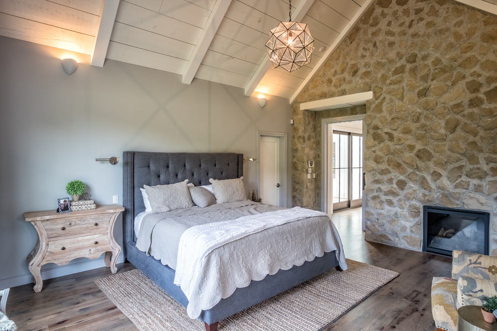Idéer för att renovera ett stort eklektiskt sovrum, med vita väggar, mellanmörkt trägolv, en standard öppen spis och en spiselkrans i sten