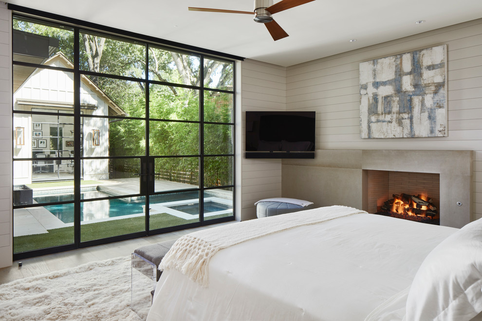 Inspiration for a rural master bedroom in Austin with a standard fireplace, a concrete fireplace surround and beige walls.