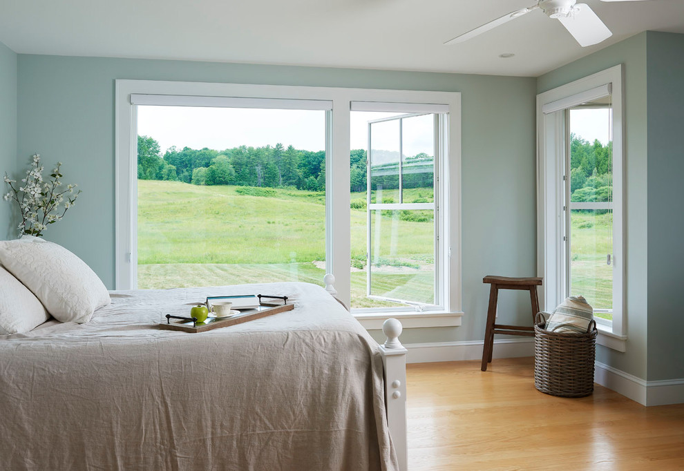 Medium sized farmhouse bedroom in Portland Maine with blue walls, medium hardwood flooring and brown floors.