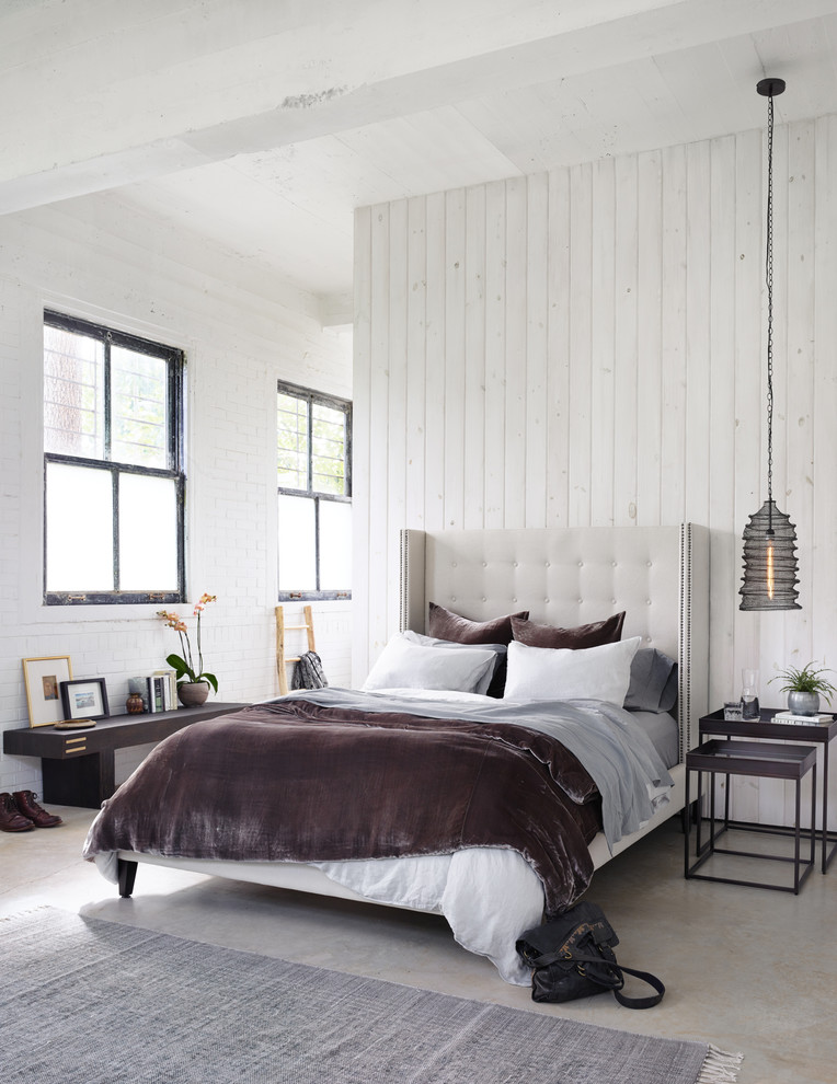 Esempio di una camera da letto stile loft country di medie dimensioni con pareti bianche, pavimento in cemento e pavimento grigio