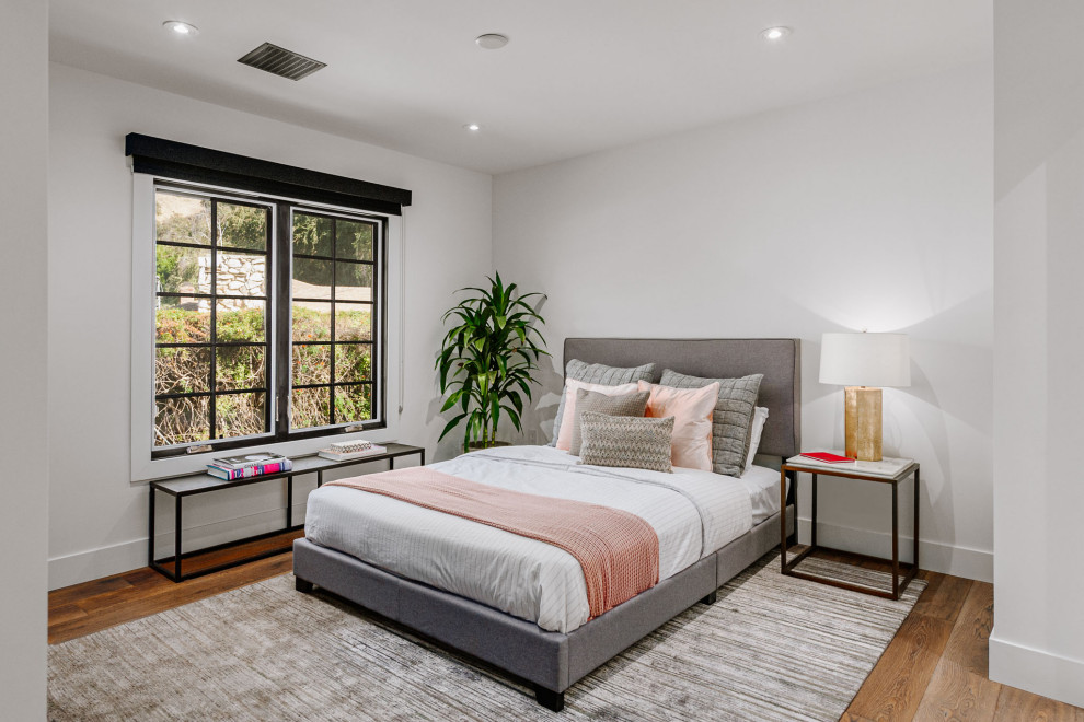 Modelo de habitación de invitados campestre de tamaño medio con paredes blancas y suelo de madera en tonos medios