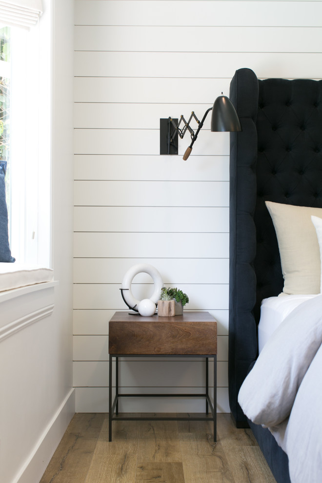 Modelo de habitación de invitados campestre de tamaño medio sin chimenea con paredes blancas y suelo de madera en tonos medios