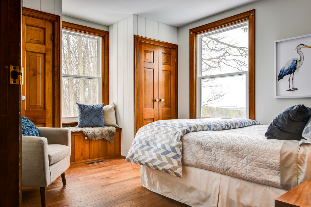 Inspiration for a farmhouse bedroom in Toronto with white walls, medium hardwood flooring and brown floors.