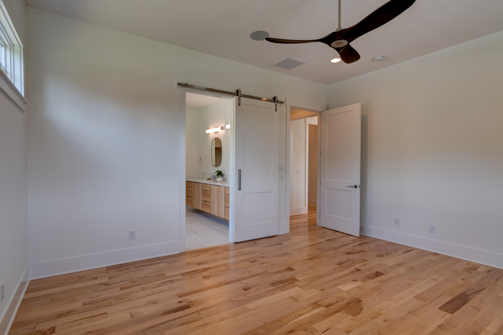 Example of a mid-sized farmhouse master light wood floor and brown floor bedroom design in Indianapolis with white walls