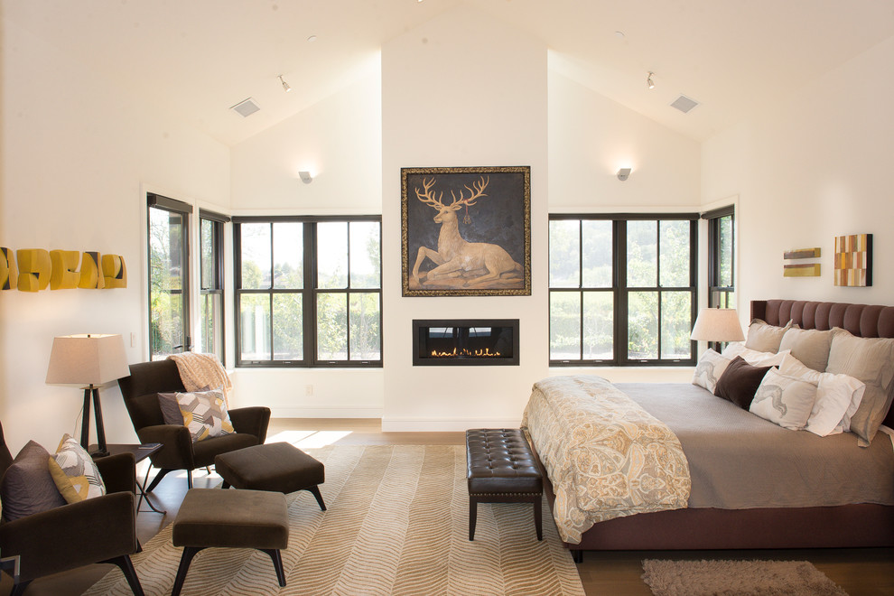 サンフランシスコにある広いトランジショナルスタイルのおしゃれな主寝室 (淡色無垢フローリング、横長型暖炉、白い壁、漆喰の暖炉まわり、ベージュの床) のレイアウト
