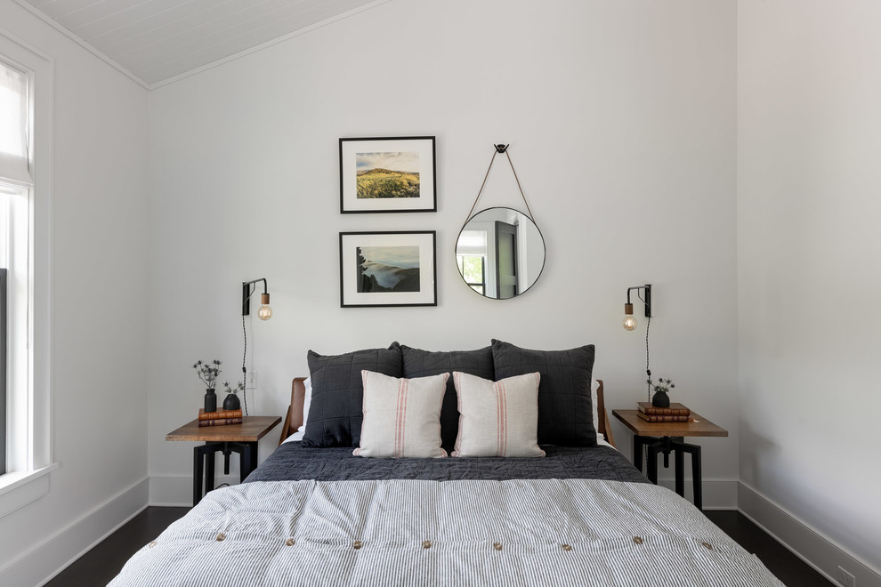 Modelo de habitación de invitados de estilo de casa de campo de tamaño medio con paredes blancas, suelo de madera oscura y suelo marrón
