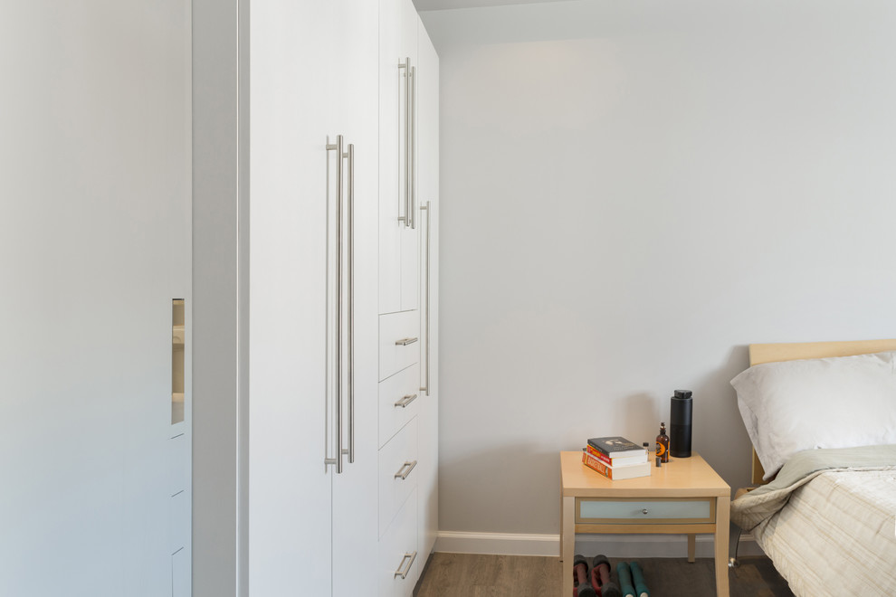 Inspiration pour une chambre parentale design de taille moyenne avec un mur blanc et un sol en bois brun.