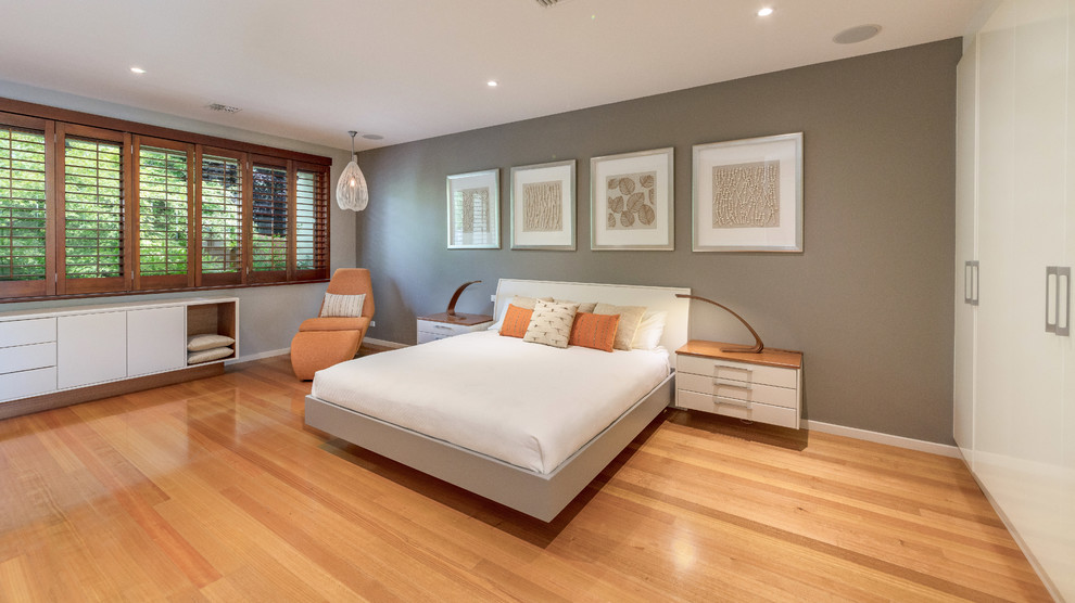 Exempel på ett modernt sovrum, med grå väggar, mellanmörkt trägolv och brunt golv