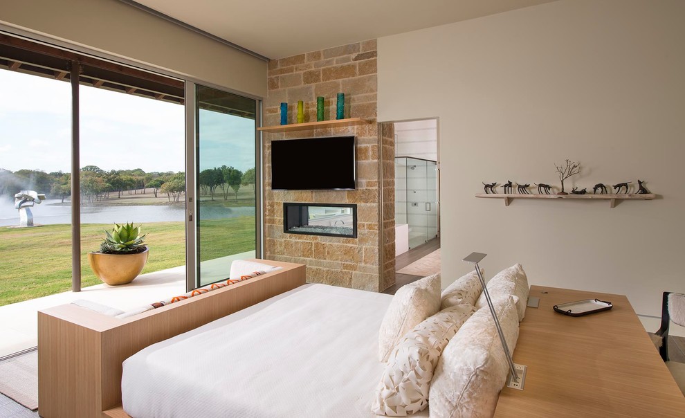 Пример оригинального дизайна: гостевая спальня среднего размера, (комната для гостей) в стиле ретро с бежевыми стенами, полом из керамогранита, двусторонним камином и фасадом камина из камня