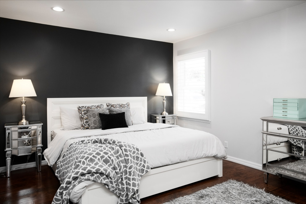This is an example of a small modern master bedroom in Los Angeles with black walls, dark hardwood flooring and brown floors.