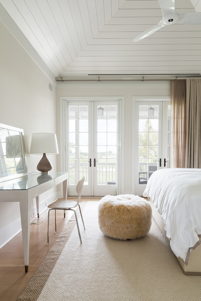 Diseño de dormitorio costero con paredes beige, suelo de madera en tonos medios, suelo beige y con escritorio