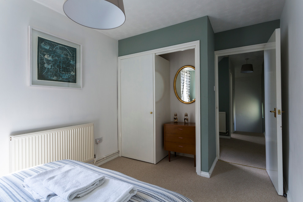 This is an example of a medium sized contemporary guest bedroom in Kent with multi-coloured walls and carpet.
