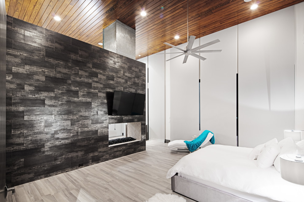 Imagen de dormitorio principal minimalista grande con paredes blancas, suelo de baldosas de porcelana, chimenea de doble cara y marco de chimenea de baldosas y/o azulejos