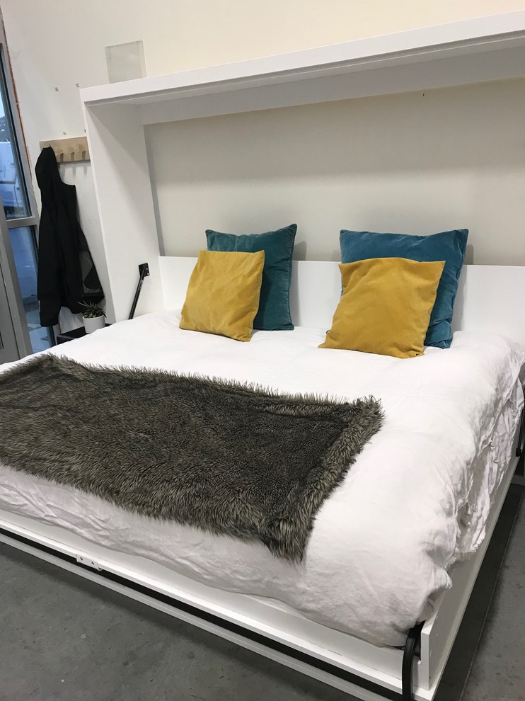 Modelo de dormitorio minimalista pequeño con paredes blancas, suelo de cemento y suelo blanco