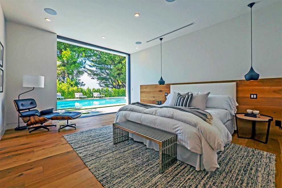Mittelgroßes Modernes Hauptschlafzimmer ohne Kamin mit weißer Wandfarbe, braunem Holzboden und braunem Boden in New York