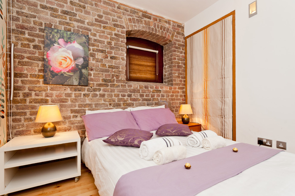 Ejemplo de habitación de invitados bohemia pequeña con paredes blancas y suelo de madera clara