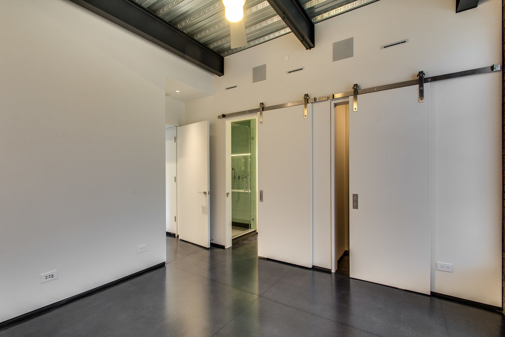 Cette image montre une chambre d'amis urbaine avec un mur blanc, sol en béton ciré et un sol noir.
