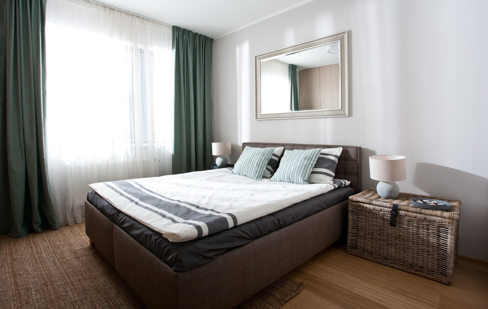 Imagen de dormitorio principal contemporáneo pequeño sin chimenea con paredes grises y suelo de contrachapado