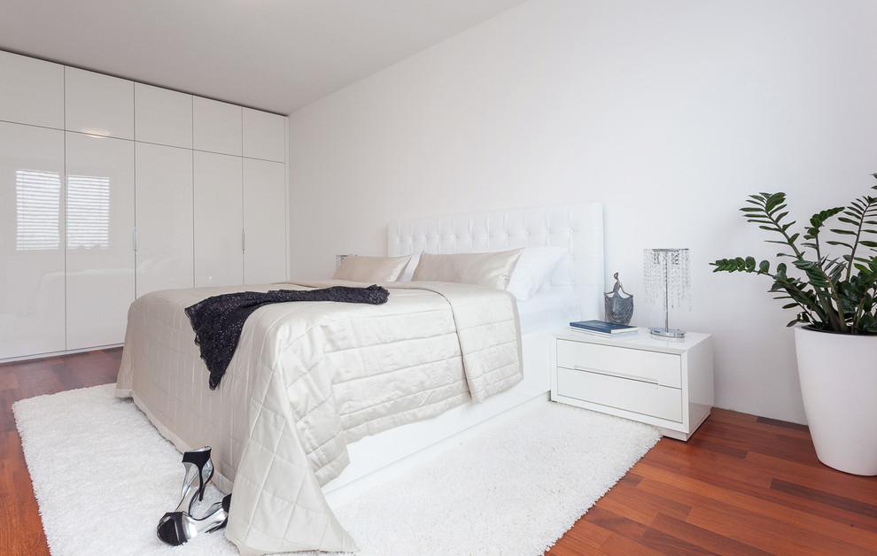 На фото: хозяйская спальня среднего размера в стиле модернизм с белыми стенами и деревянным полом без камина с