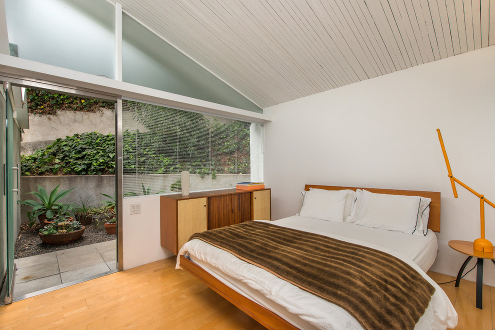 Foto de dormitorio retro con paredes blancas y suelo de madera en tonos medios