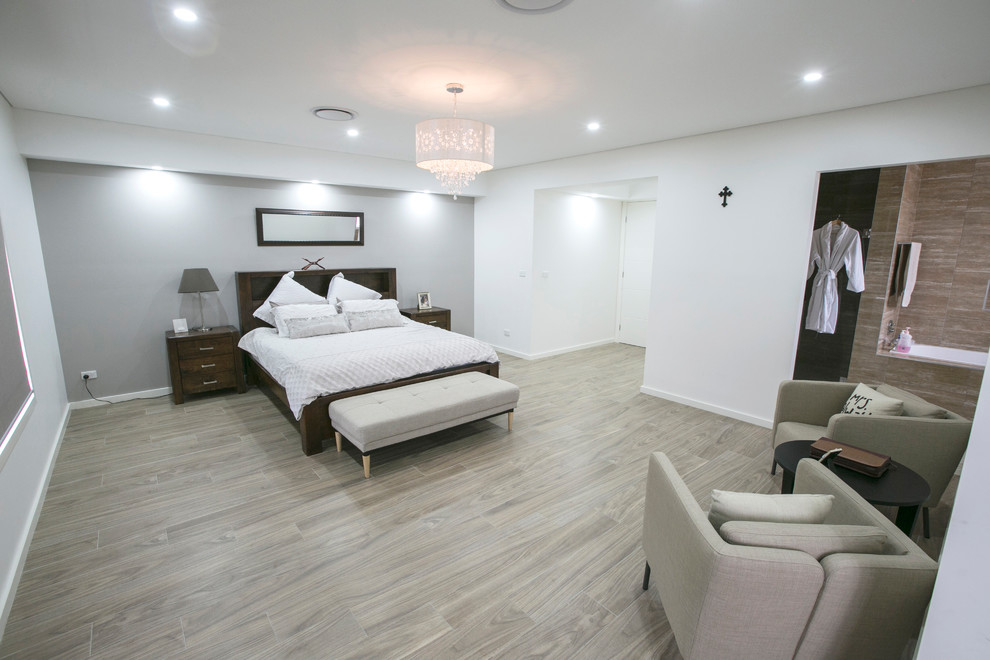 На фото: большая хозяйская спальня в современном стиле с белыми стенами, полом из керамогранита и коричневым полом с