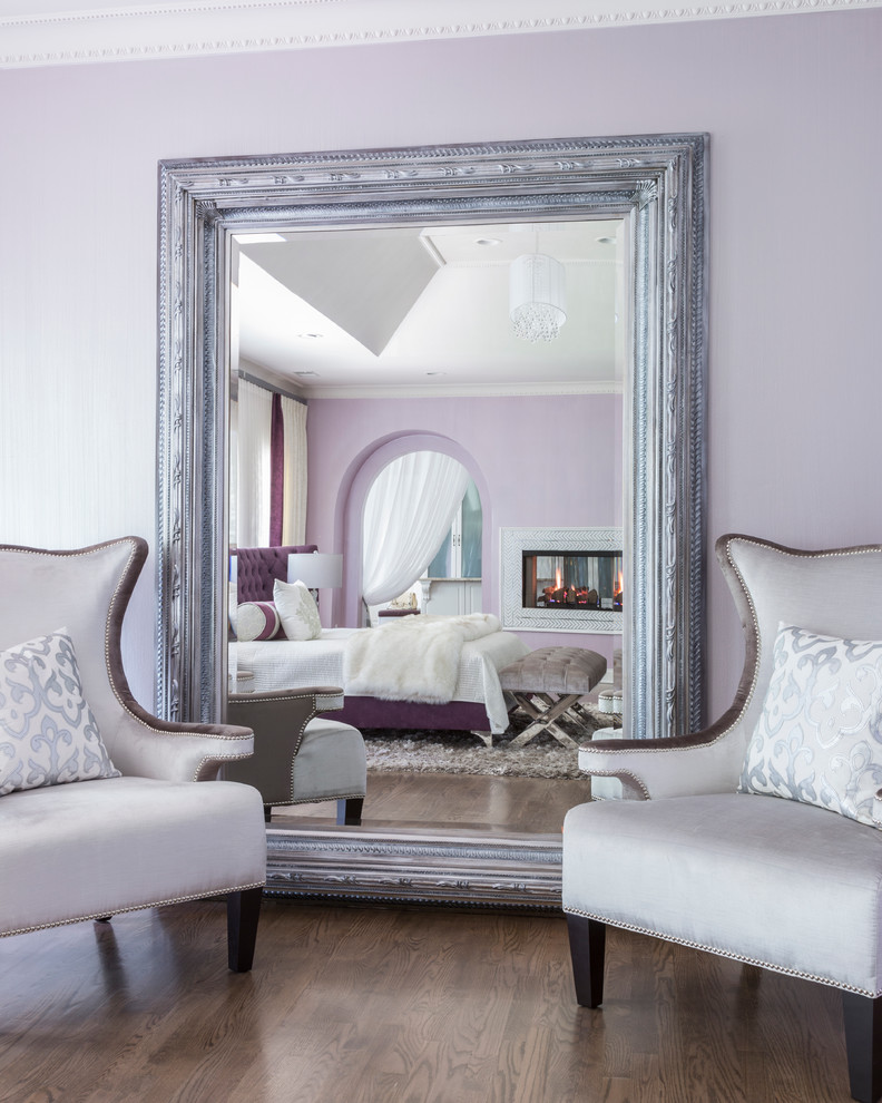 Imagen de dormitorio principal moderno grande con paredes púrpuras, suelo de madera en tonos medios, chimenea de doble cara y marco de chimenea de baldosas y/o azulejos
