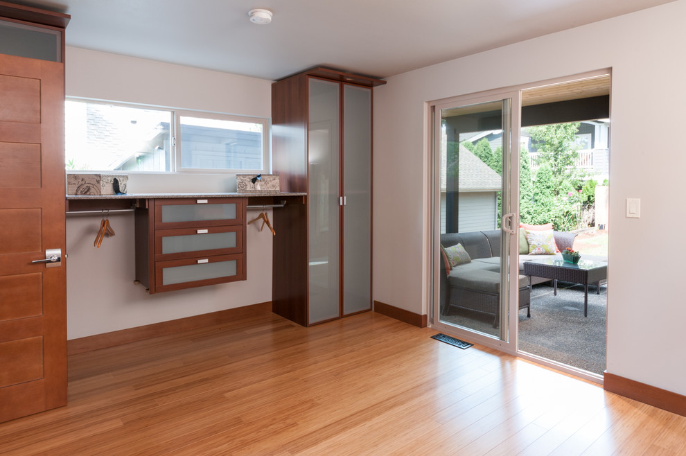 Aménagement d'une chambre parentale contemporaine de taille moyenne avec un mur gris et un sol en bois brun.