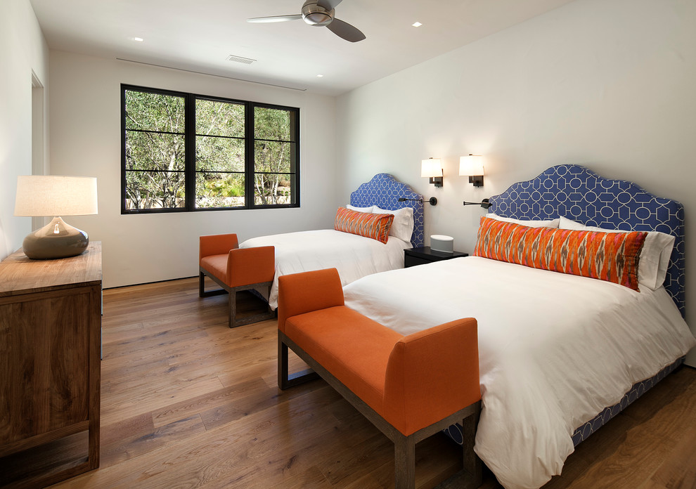 Modelo de habitación de invitados mediterránea de tamaño medio sin chimenea con paredes blancas y suelo de madera en tonos medios