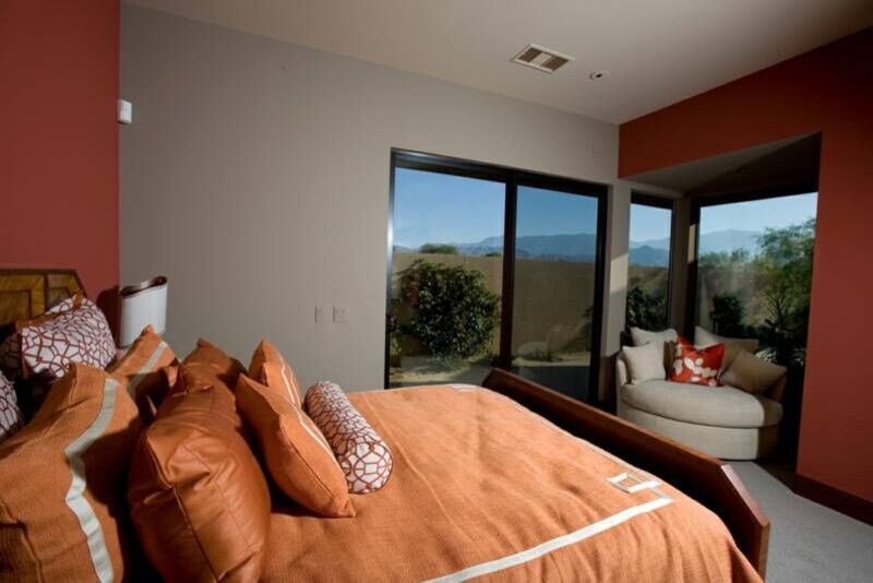 This is an example of an expansive contemporary guest bedroom in Los Angeles with orange walls and carpet.