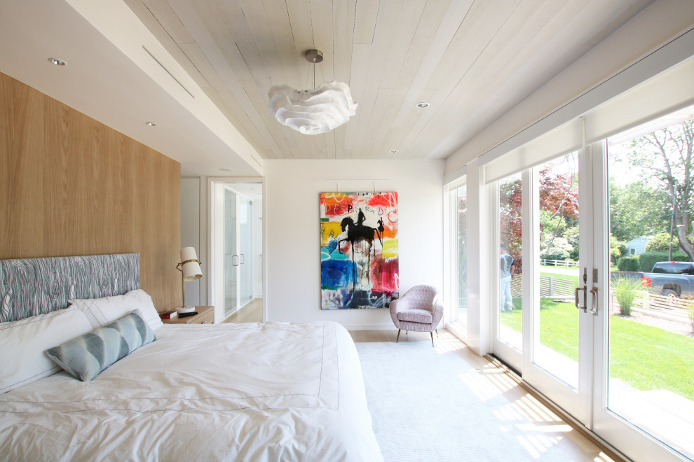 Inspiration for a large modern master bedroom in New York with white walls, light hardwood flooring and no fireplace.