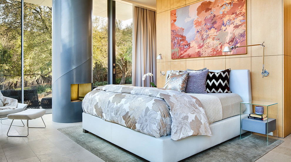 Ejemplo de dormitorio principal moderno de tamaño medio con paredes blancas, suelo de piedra caliza, marco de chimenea de metal y estufa de leña