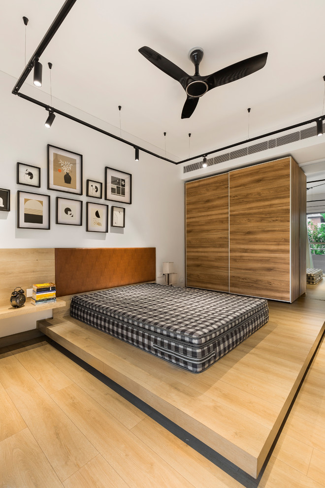 Immagine di una camera da letto contemporanea con pareti bianche, parquet chiaro e pavimento beige