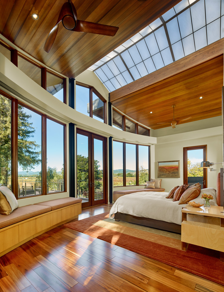 Medium sized modern master bedroom in San Francisco with beige walls, medium hardwood flooring, a corner fireplace and feature lighting.