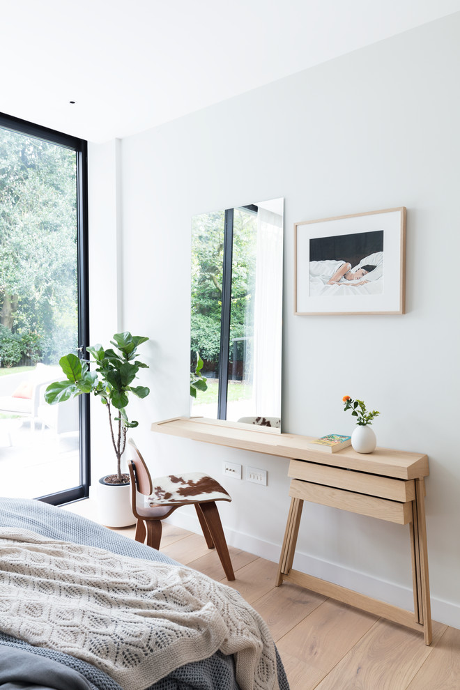 Imagen de habitación de invitados actual de tamaño medio con paredes blancas y suelo de madera clara