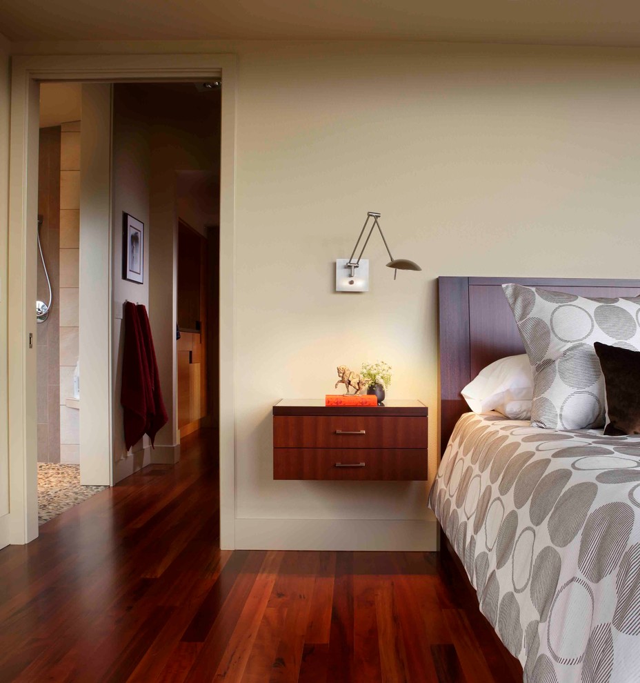 Modelo de dormitorio principal moderno grande con paredes beige y suelo de madera en tonos medios